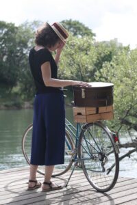 femme avec un chapeau canotier au bord de l'eau avec un vélo