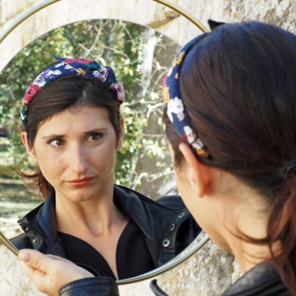 femme se regardant dans un miroir avec un serre tete à fleurs