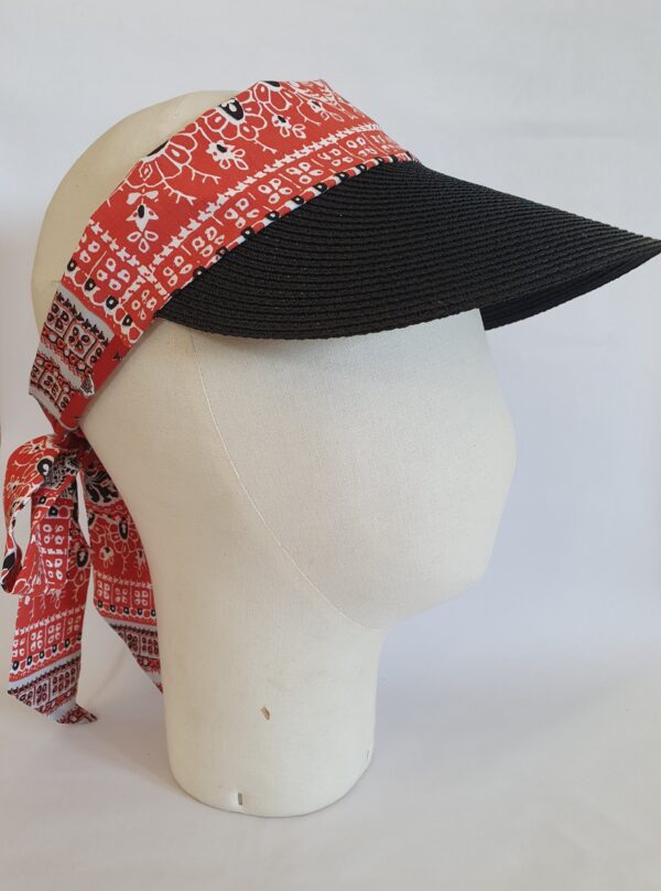 Visière en paille noire avec foulard imprimé bandana rouge sur marotte et fond blanc