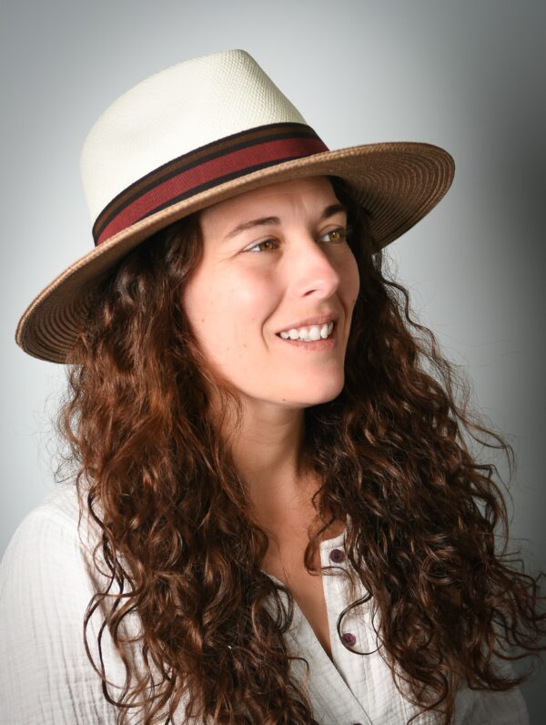 femme brune souriante avec chapeau unisexe fedora blanc et praline